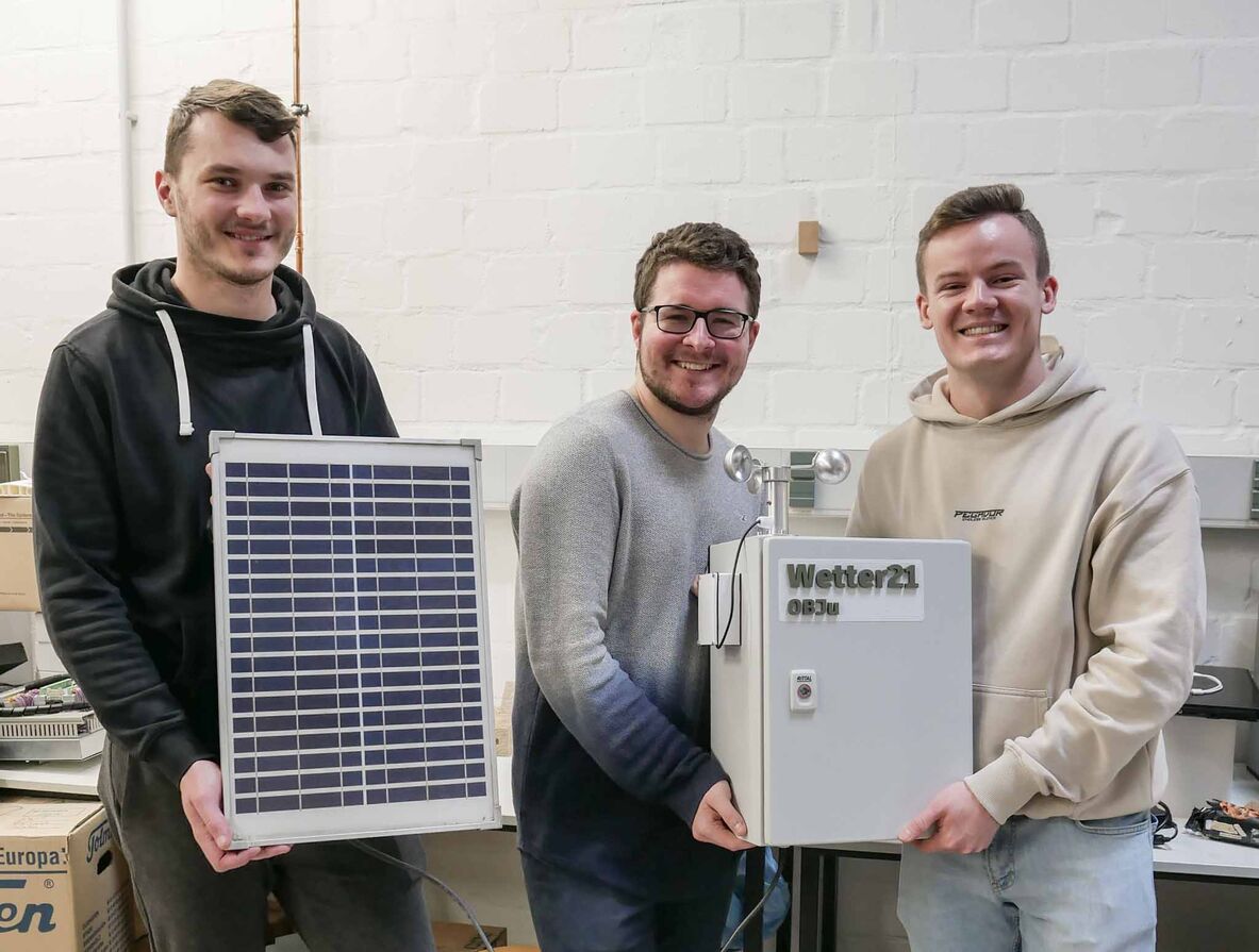 Die Studierenden Julian Hilz (von links), Björn Henning und Otis von Busch halten die Wetterstation samt Photovoltaik-Modul.