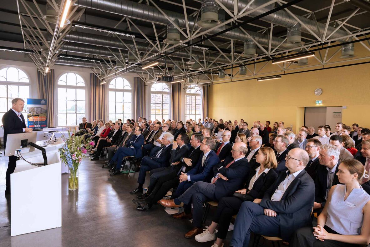 Das Publikum sitzt in der Aula und hört dem Festredner Pro. Dr. Ulf-Daniel Ehlers zu, der im Bild rechts vor dem Publikum steht.