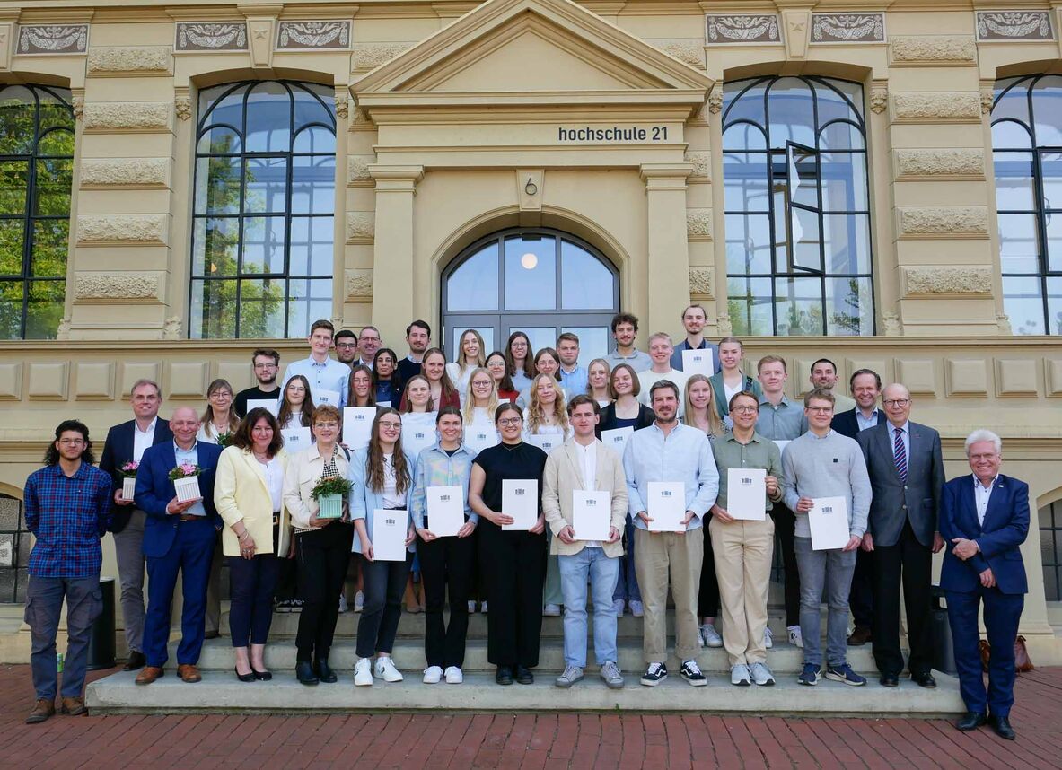 Die Stipendiatinnen und Stipendiaten stehen mit dem Auswahlgremium, der Hochschulleitung sowie Vertreterinnen und Vertretern der Stiftungen und Fördereinrichtungen vor dem Hochschulgebäude auf der Eingangstreppe.