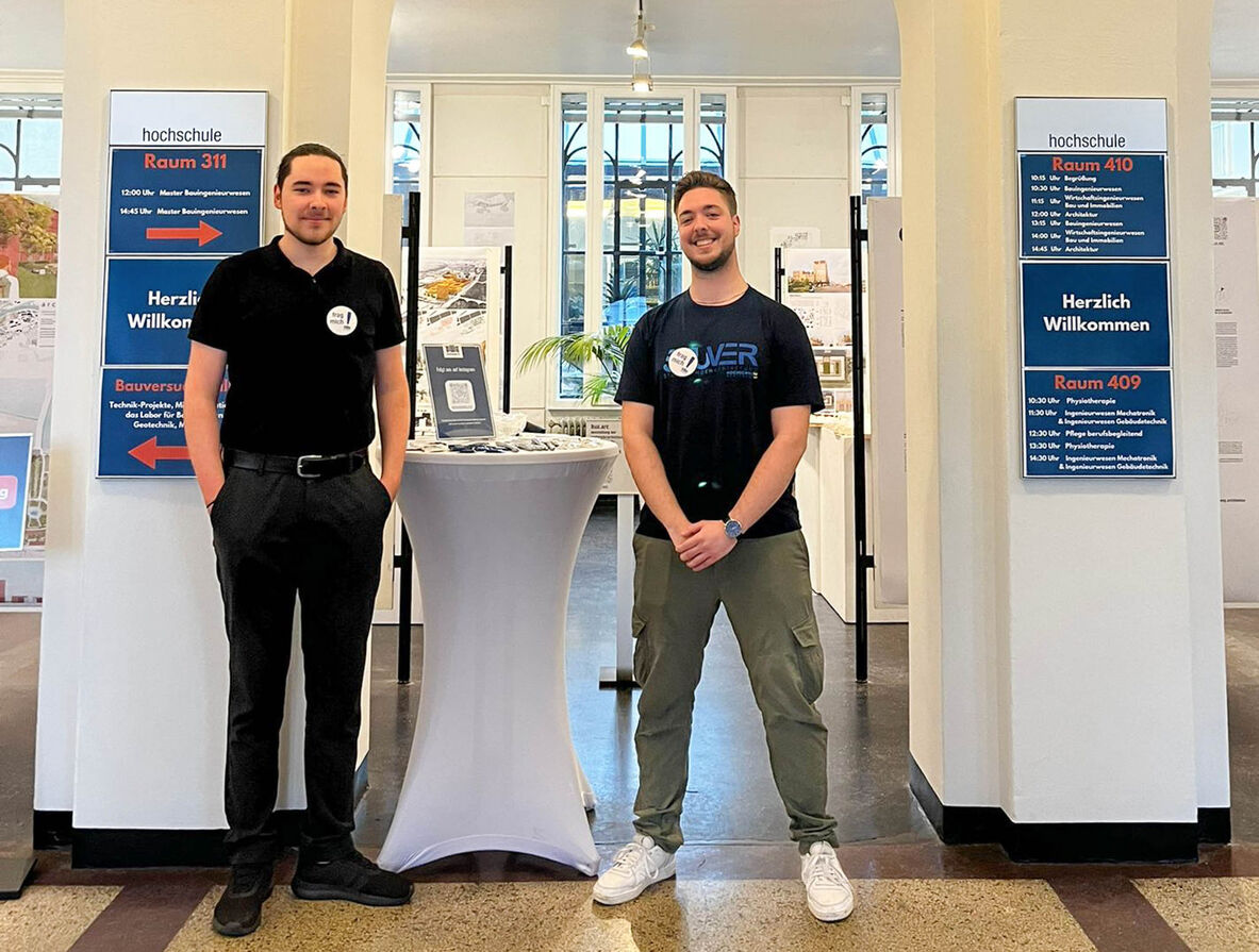 Zwei lächelnde Studenten stehen am Infostand