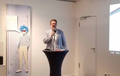 Prof. Dr.-Ing. Karsten Ley steht mit Mikrofon an einem Stehtisch.