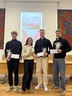 Preisträger Architektur Rotenburg 2025 Drei Studenten und eine Studentin mit weißen Briefumschlägen und kleinen Geschenken stehen zusammen.