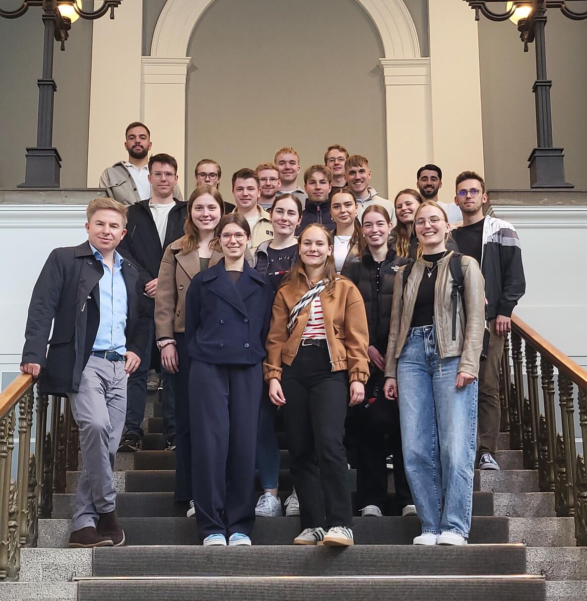 Die WBI-Studierenden stehen mit Prof. Dr. Benjamin Beug auf einer Treppe im Gebäude der Handelskammer Hamburg.