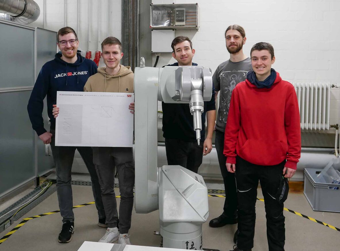 Die Studierenden Marvin Stöckmann, Nico Schnackenberg, Hannes Kopper, Frederic Schmehl und Nele Bendler mit dem Industrieroboter
