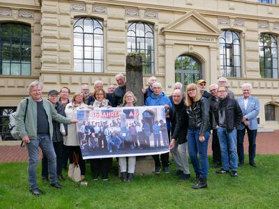 Gruppenfoto der ehemaligen Architekturstudierenden mit ihrem damaligen Professor Eduard Stura und dem jetzigen Hochschulpräsident Prof. Dr.-Ing. Ingo Hadrych mit dem Obelisken vor dem Hochschulgebäude.