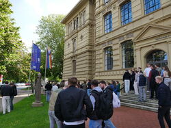 Teilnehmende beim Hissen der Progress Pride Flagge für den Deutschen Diversity Tag vor der hochschule 21