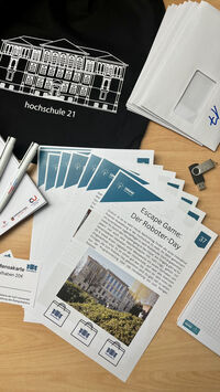 Sammlung der Materialien wie Briefumschläge, Anleitung und Turnbeutel mit Hochschul-Logo